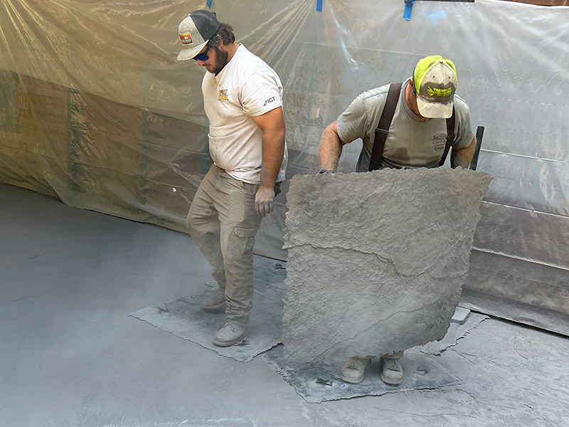 Trapanier-Masonry-Team-2 A pair of employees is stamping texture into a patio made of concrete.