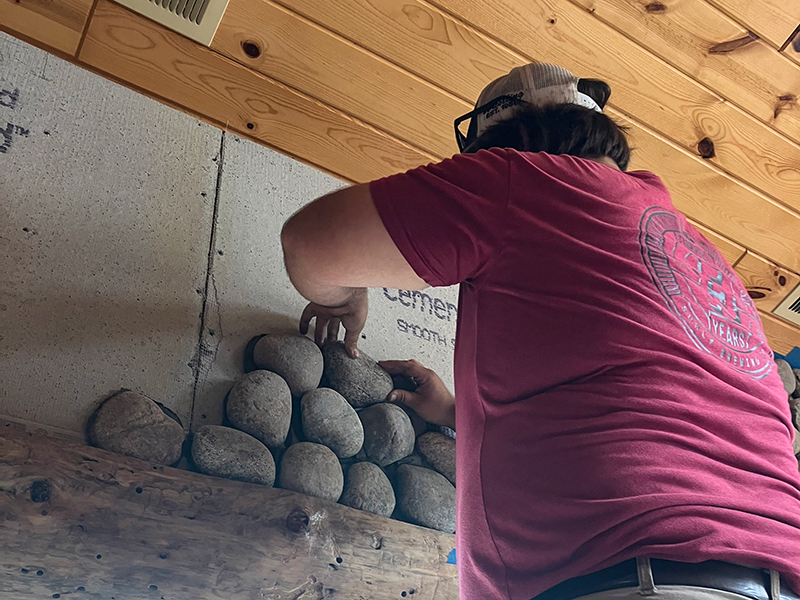 Trapanier-Masonry-Team-3 An employee is adding rocks to a large stone archway.