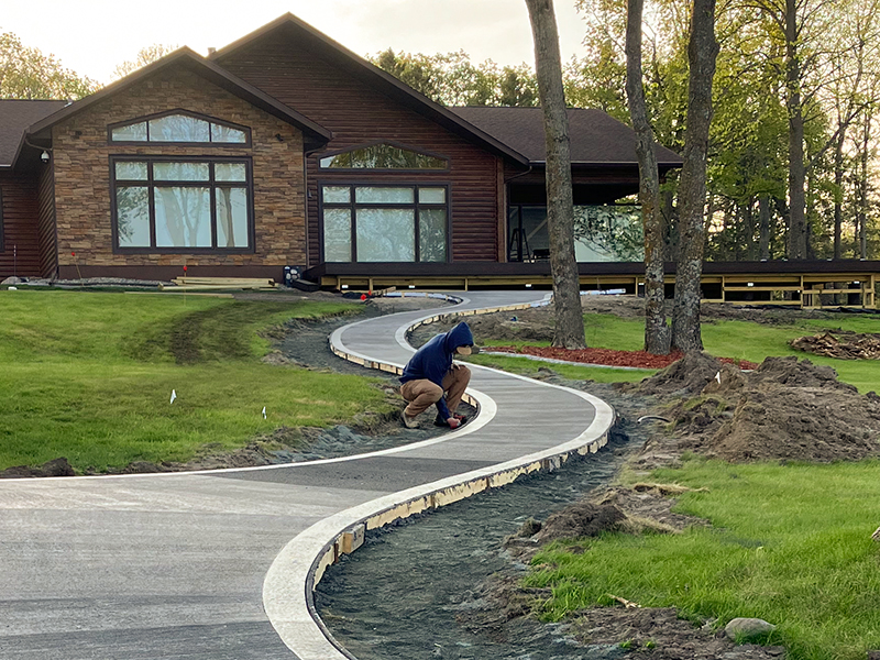 Trapanier-Masonry-Team-5 An employee is putting finishing touches on a large curvy sidewalk.