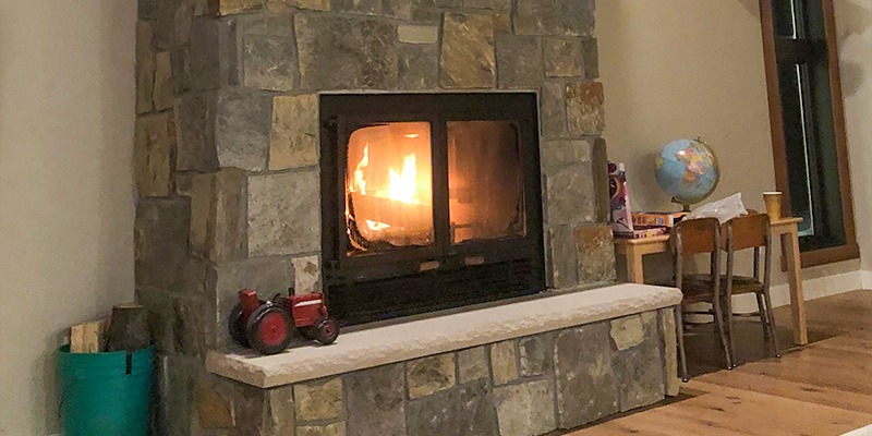 A warm lit fireplace made from stone blocks.
