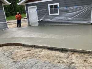 A concrete driveway and patio outside a garage but connected to the house as well.