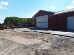 A concrete driveway is being built. Dirt work is going on in the background.