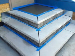 A set of angles steps in the corner of a house leading to a door.