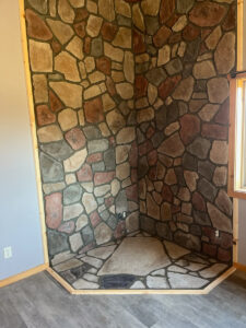 Custom natural stone fireplace surround and hearth under construction by Trepanier Masonry in Bemidji, MN.